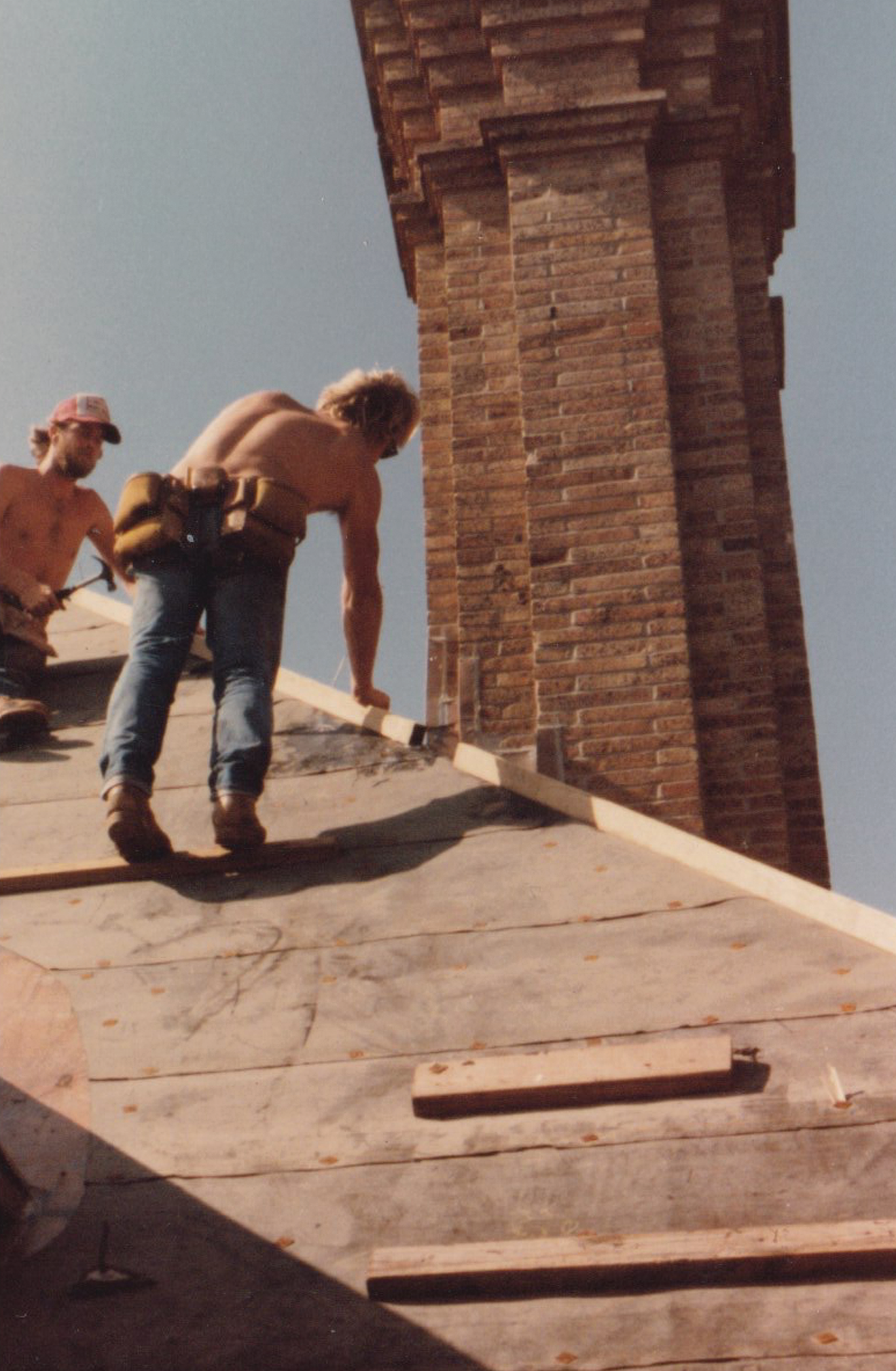 Roofing crew working near a brick chimney