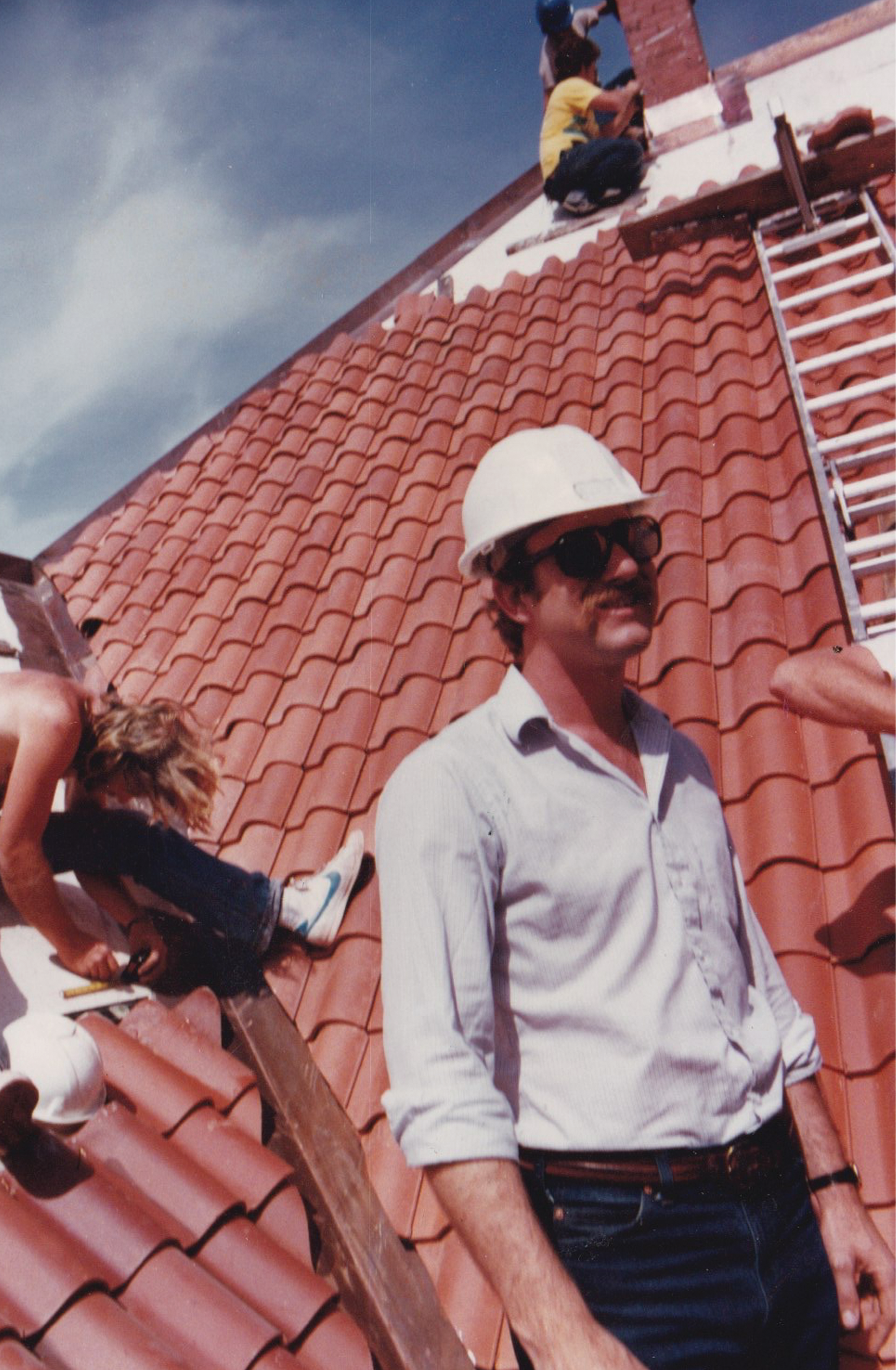 Foreman in hard hat overseeing crew on clay tile roof