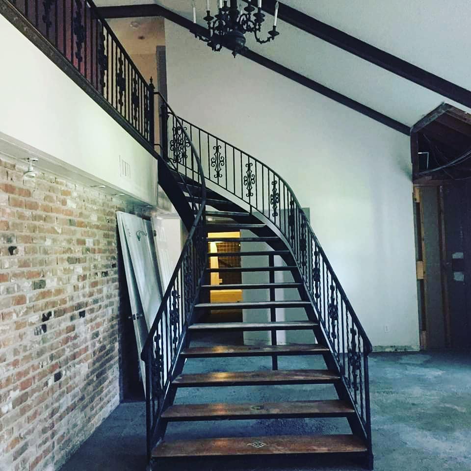 Curved staircase with ornate iron railings and exposed brick