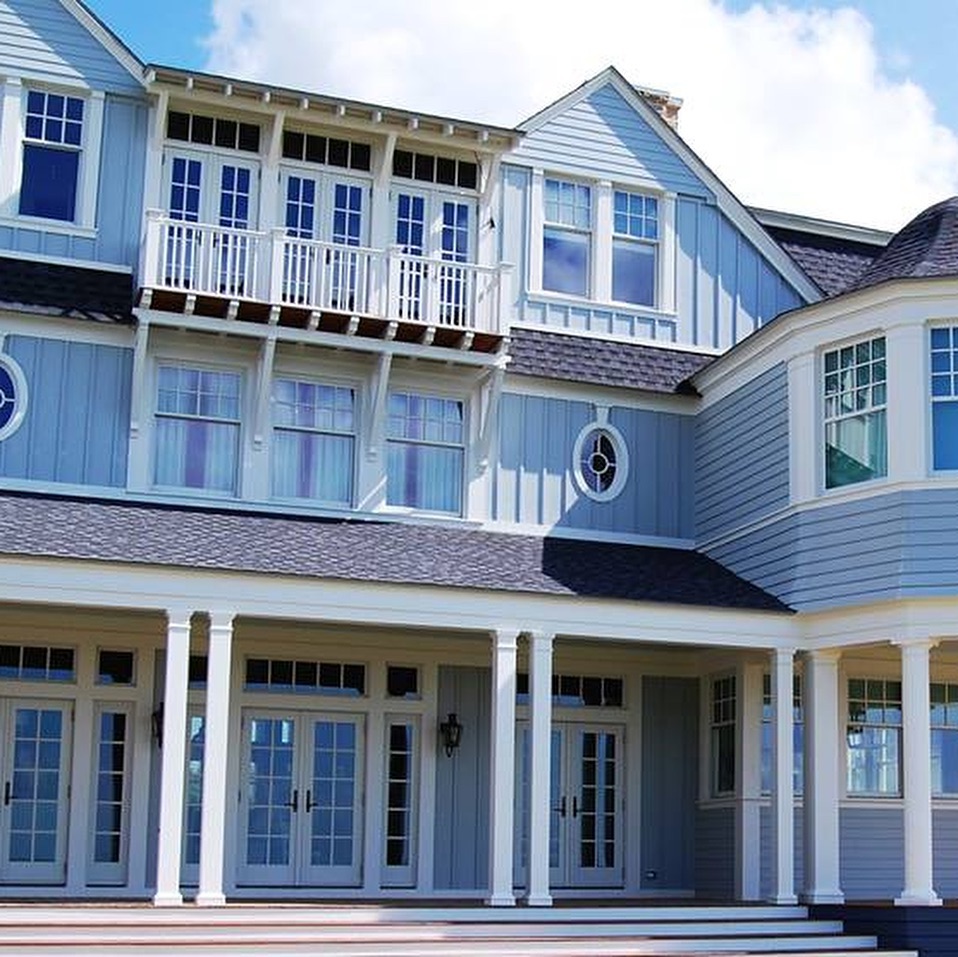 Large coastal home with blue siding and covered balconies