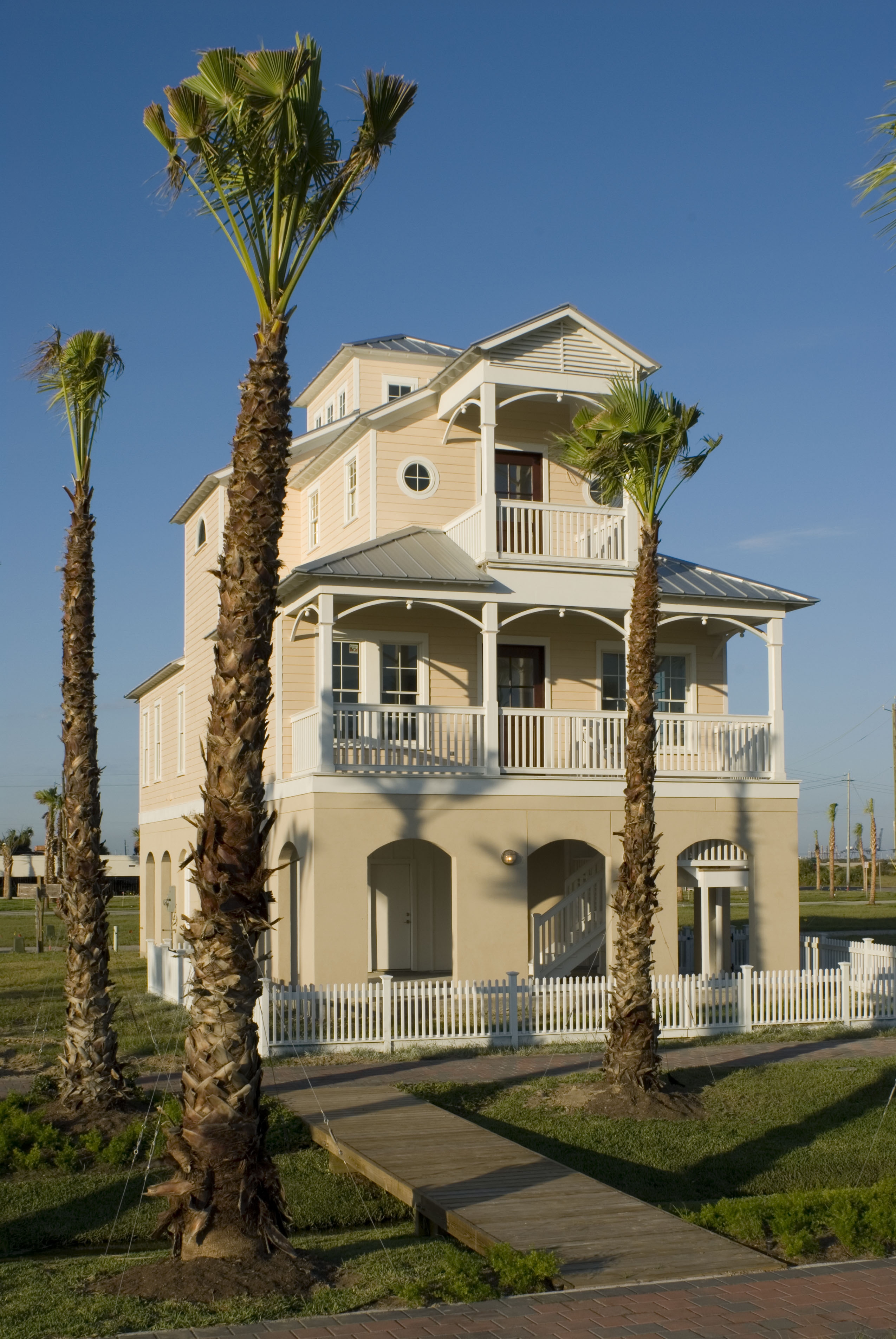 Three-story tan coastal home with covered porches