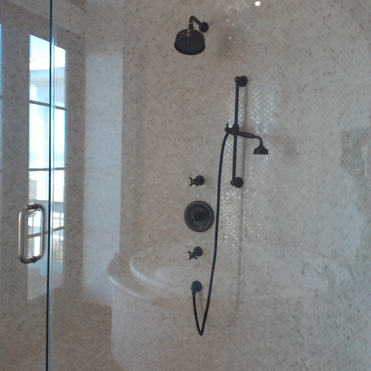 Marble shower with stripe tile accent and bronze fixtures