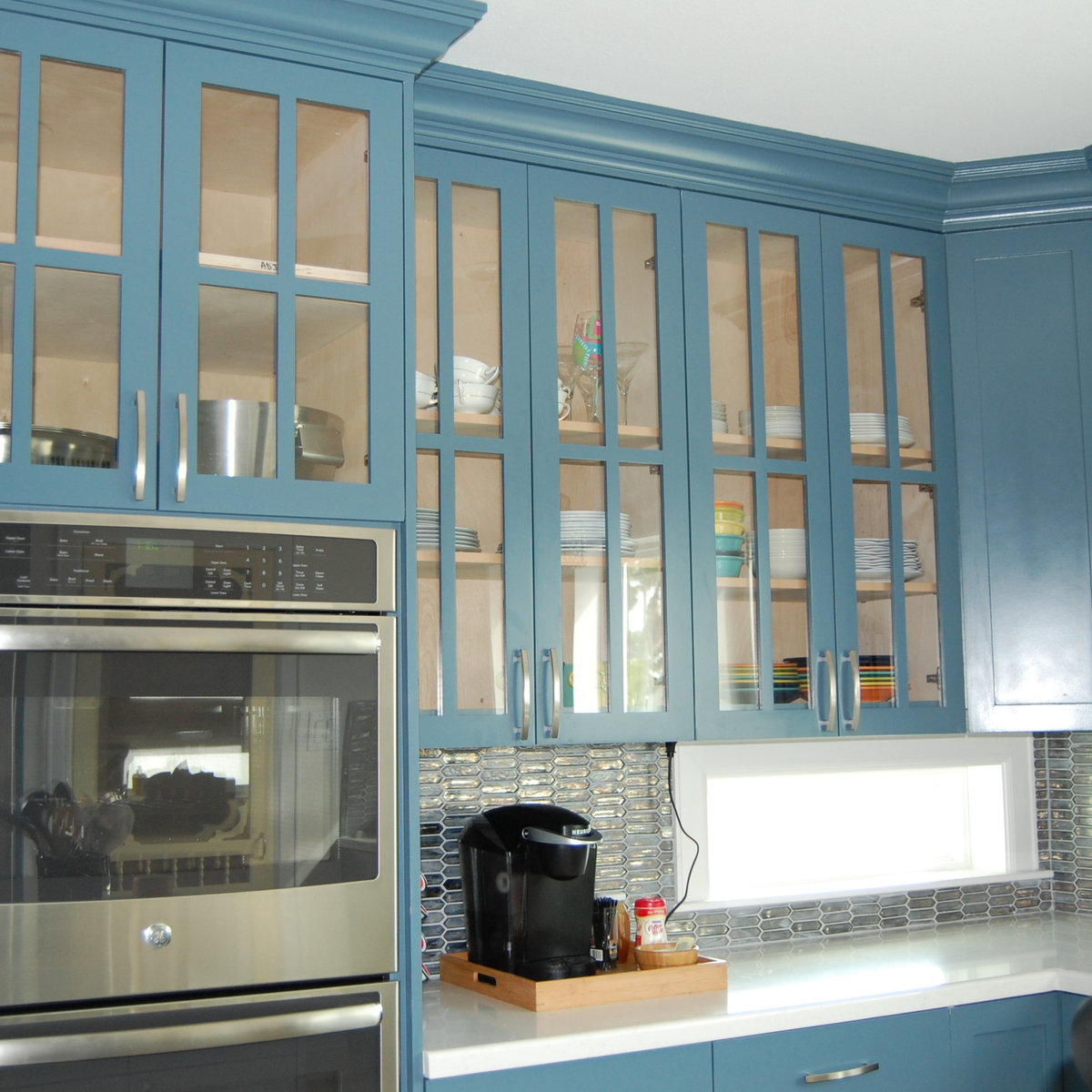 Kitchen with blue glass-front cabinets and geometric backsplash