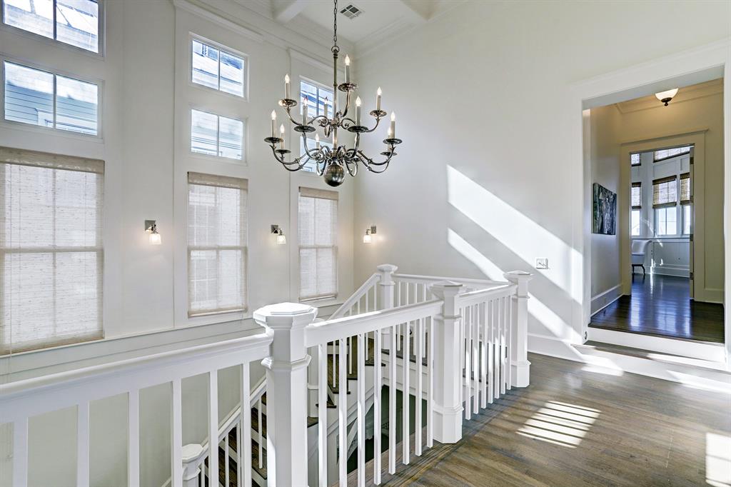 Second-floor landing with chandelier and tall windows